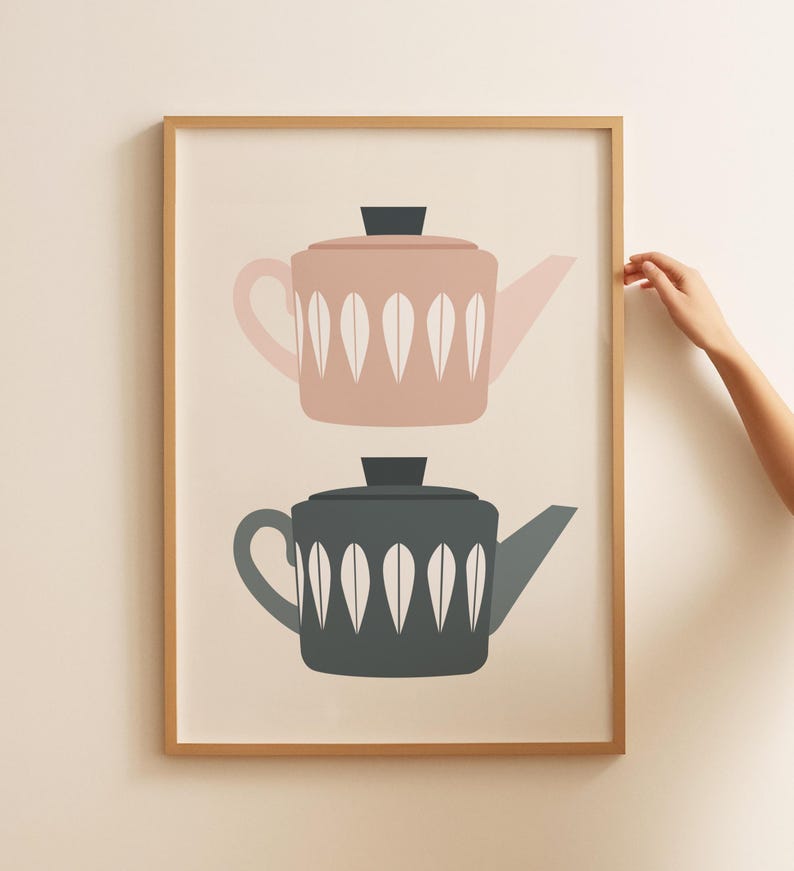 May include: A framed print of two teapots, one pink and one gray, with white leaf designs. The teapots are stacked on top of each other.