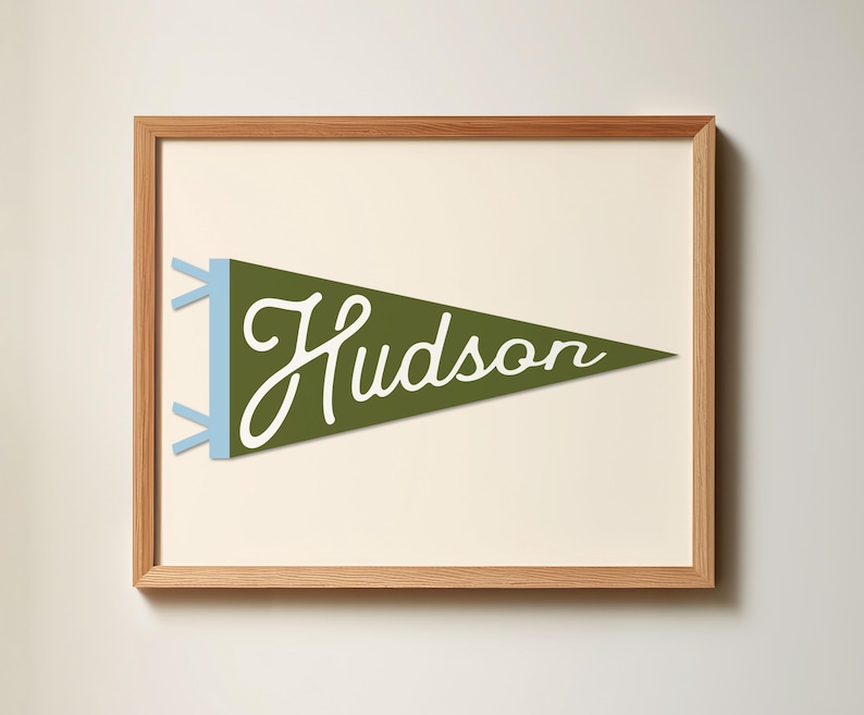 May include: A framed print of a green pennant with the word "Hudson" written in white script. The pennant has blue tassels.