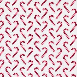 May include: A white fabric with a repeating pattern of red candy canes. The candy canes are arranged in a diagonal pattern.