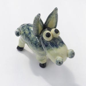 May include: A ceramic donkey figurine with blue and white glaze. The donkey has large, black eyes and a whimsical expression.