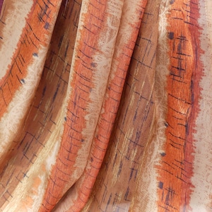 May include: A close-up of a fabric with a brown and orange striped pattern. The fabric has a subtle texture and a slightly sheer appearance.