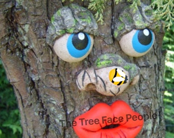Funny faces for trees with blue eyes and red lips.   Lady face sculpture for garden decoration, silly yard art.  Christmas tree decoration