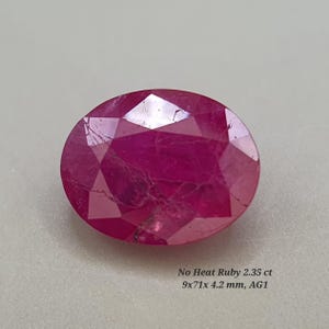 Op de afbeelding: Een gefacetteerde, ovale robijn edelsteen met een dieprode kleur. De edelsteen is gemarkeerd met "No Heat Ruby 2.35 ct" en meet 9x7,1x4,2 mm. De steen ligt tegen een neutrale achtergrond.