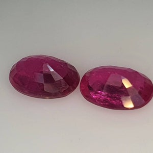 Op de afbeelding: Twee ovale, gefacetteerde robijn edelstenen. De robijnen zijn diep roze van kleur en hebben een hoge mate van glans.