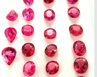 May include: A selection of bright pink gemstones, cut into various shapes. The gemstones include oval, round, and pear-shaped cuts. They are arranged in rows, displaying their colour and clarity. The light catches the facets, creating a sparkling effect. Measurements are in cm.