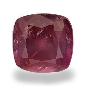 May include: A cushion-cut ruby gemstone with a deep red hue. The gemstone has a faceted surface that reflects light, creating a sparkling effect. The ruby is set against a white background, highlighting its color and clarity.