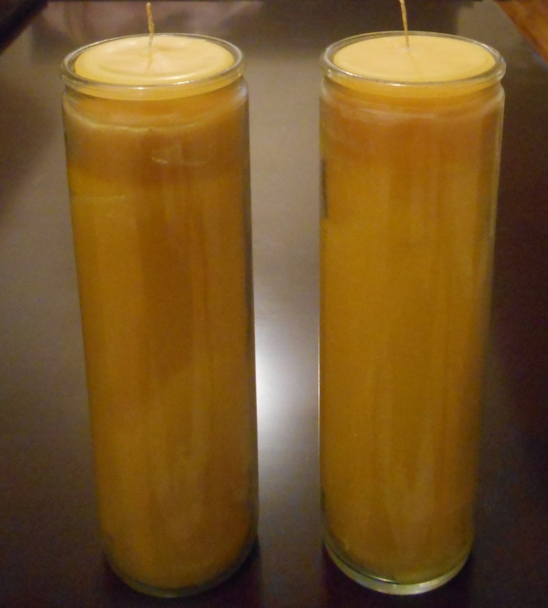 May include: Two tall, clear glass candle holders with yellow candles inside. The candles are almost completely melted down, leaving a small amount of wax at the top.