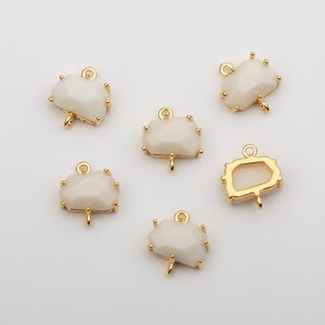 May include: Six gold-tone metal charms with white stone accents. The charms have a loop at the top for attaching to jewelry or other crafts.