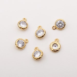 May include: Six gold-tone charms with clear round rhinestones. Each charm has a loop for attaching to a necklace or bracelet.