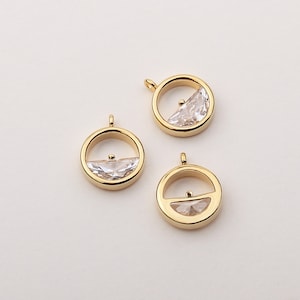 May include: Three gold-toned pendant charms with a clear crystal half-moon shape inside each circle.
