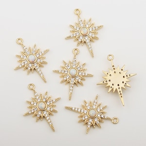 May include: Six gold starburst charms with clear iridescent stones in the centre. Each charm has a loop at the top for attaching to jewellery.