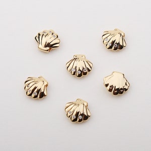 May include: Six gold-tone seashell charms with clear rhinestone accents.