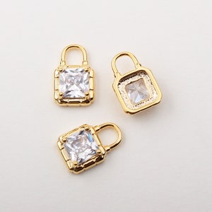 May include: Three gold lock charms with clear square rhinestones. The charms are perfect for adding a touch of sparkle to jewelry or crafts.