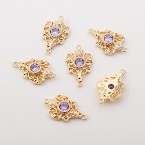 May include: Six gold-tone metal charms with ornate filigree designs and a single purple rhinestone in the centre of each charm. Each charm has two loops for attaching to jewellery.