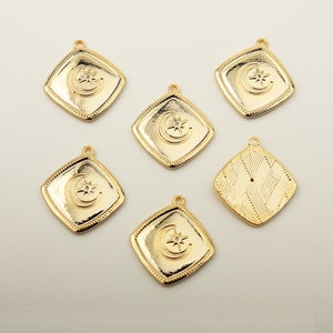 Op de afbeelding: Zes goudkleurige metalen bedels met een halve maan en ster ontwerp. De bedels zijn vierkant met een decoratieve rand.