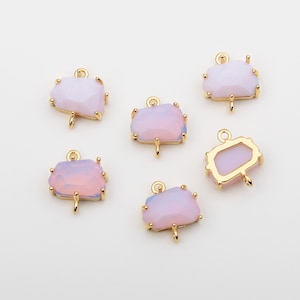 May include: Six gold-toned pendant charms with a pale pink iridescent glass stone. Each charm has a loop at the top for attaching to a necklace or bracelet.