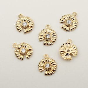 Puede incluir: Seis colgantes dorados con forma de flor de margarita con un centro de cristal transparente. Cada colgante tiene un lazo en la parte superior para una fácil fijación a la joyería. Ideal para crear collares, pulseras y pendientes.