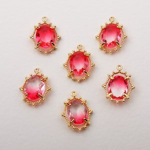 Puede incluir: Seis colgantes de tono dorado con piedras de vidrio ovaladas de color rosa engastadas en un marco decorativo.