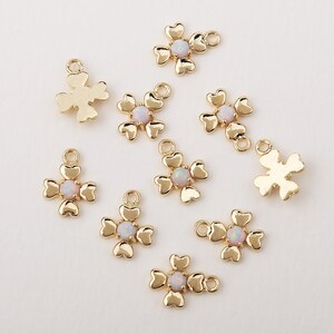 May include: Gold-tone flower charms with white opal centers. Each charm has a loop for attaching to jewelry.