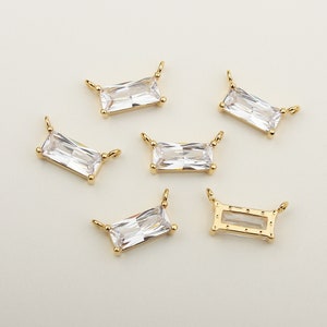 Puede incluir: Seis colgantes de tono dorado con piedras de cristal rectangulares transparentes. Un colgante tiene un marco rectangular hueco.