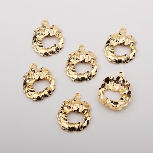 Puede incluir: Seis abalorios de metal dorado en forma de corona con una abertura ovalada. Los abalorios tienen un diseño texturizado y ondulado.
