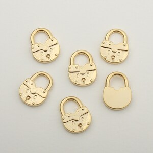 May include: Six gold-tone padlock charms with a keyhole detail. The charms are about 1 inch in size and have a textured surface.