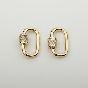 May include: Two gold-toned oval-shaped clasps with a clear crystal-encrusted barrel in the center.