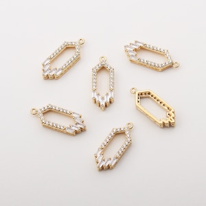 May include: Six gold-toned pendant charms with clear crystal embellishments. Each charm features a geometric shape with a cutout in the center. The charms have a loop at the top for attaching to a necklace or bracelet.