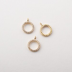 May include: Three gold-toned circle pendants with a clear crystal embellishment around the edge. Two of the pendants have a clear crystal design, and one has a smooth, plain edge.