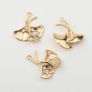 May include: Three gold-tone ginkgo leaf charms with clear rhinestone accents. Each charm has a loop for attaching to jewelry.