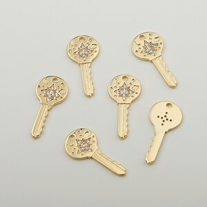 May include: Six gold-toned key charms with a star and moon design. The charms are adorned with clear rhinestones.