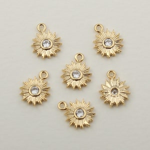 Peut inclure: Six breloques en forme d'étoile dorées avec des centres en strass transparents. Chaque breloque a une petite boucle pour l'attacher à des bijoux.