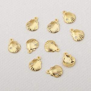 Peut inclure: Dix breloques en forme de coquillage en métal doré avec un seul strass transparent au centre de chaque coquillage. Les breloques ont une boucle en haut pour les attacher à des bijoux.