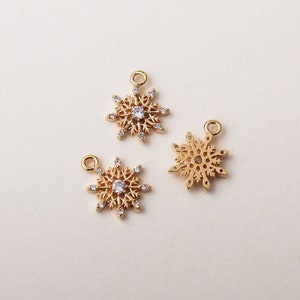 May include: Three gold snowflake charms with clear crystal accents. The charms are perfect for adding a touch of winter magic to jewelry projects.