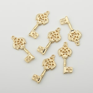 May include: Six gold-toned key charms with intricate designs. The keys have a decorative, ornate, and vintage style.