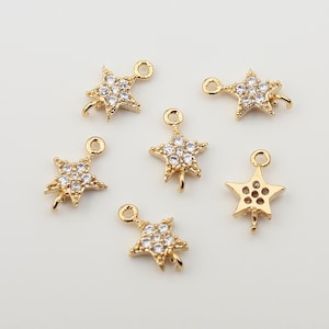 May include: Six gold-tone star-shaped charms with clear crystal accents. Each charm has a loop at the top for attaching to jewellery.