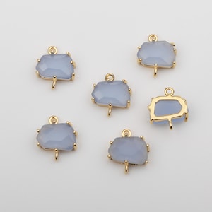May include: Six gold-toned metal charms with light blue glass inserts. The charms have a geometric shape and a loop at the top for attaching to jewelry.