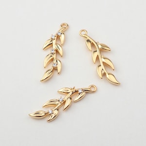 Puede incluir: Tres abalorios de hoja de oro con detalles de cristal transparente. Los abalorios tienen forma de rama con hojas.