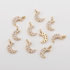 Pode incluir: Dez pingentes de lua crescente em tom dourado com detalhes em cristal transparente. Os pingentes têm um laço na parte superior para prender em joias.