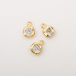 May include: Three gold-tone metal charms with a square shape and a clear rhinestone in the center.