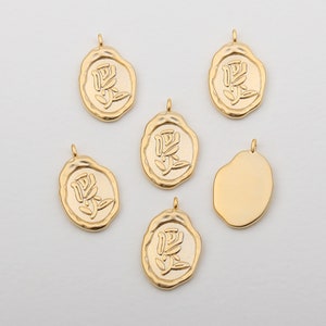 Puede incluir: Seis abalorios de metal dorado con un diseño en relieve. Cinco abalorios presentan un diseño floral estilizado y un abalorio está en blanco.