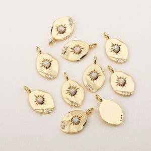 May include: Ten gold-toned oval charms with a sunburst design and a white opal stone in the center. Each charm has small clear stones around the edge.