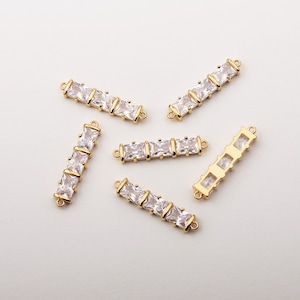 May include: Five gold-toned metal connector pieces with clear square-shaped rhinestones. Each piece has two loops on either end for attaching to jewelry.