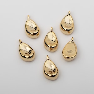 May include: Six gold-colored metal pendant charms in the shape of a teardrop with a smooth, rounded surface.