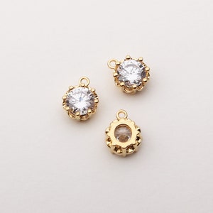 May include: Three gold-tone metal charms with clear rhinestone accents. Each charm features a round, faceted rhinestone surrounded by a decorative border.