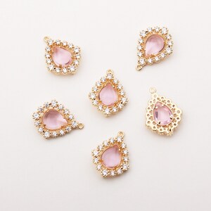 May include: Six gold-tone teardrop-shaped pendants with pink glass stones and clear rhinestone accents.