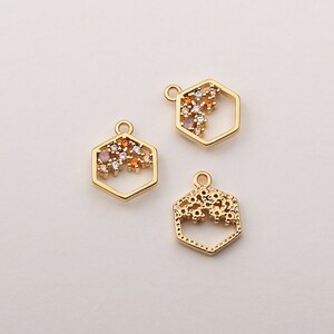 May include: Three gold-toned hexagon-shaped charms with a decorative design of small colorful gemstones. The charms have a loop at the top for attaching to jewelry.