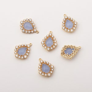 May include: Five gold-tone pendant charms with a teardrop-shaped blue stone surrounded by clear rhinestones. Each charm has a loop at the top for attaching to a necklace or bracelet.