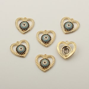 May include: Six gold heart-shaped pendants with a blue and black evil eye design. Each pendant has a loop at the top for attaching to a chain or cord.
