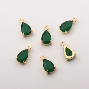 May include: Six gold-tone teardrop-shaped pendants with green glass stones. The pendants have a loop at the top for attaching to a chain or cord.